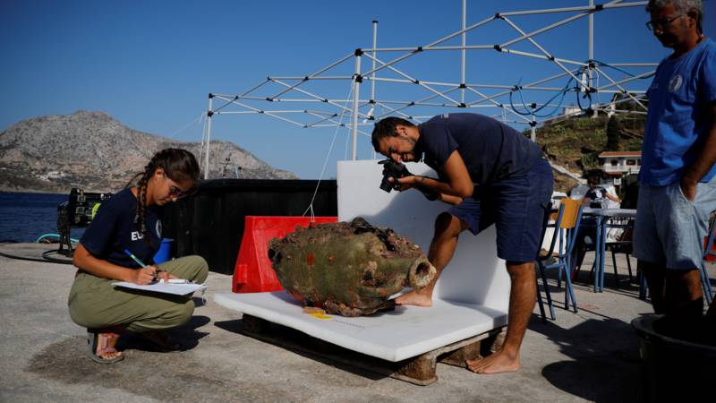 Archaeologists investigate a jug of a shipwreck