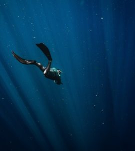 man in black wetsuit swimming in blue water